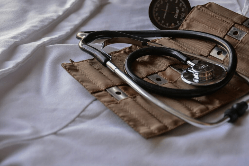 A close-up of a stethoscope and blood pressure cuff resting on a white fabric surface.